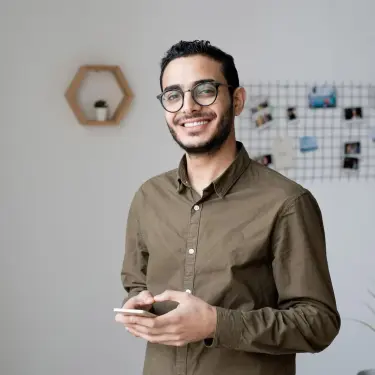 Mann hält ein Smartphone in der Hand und lacht