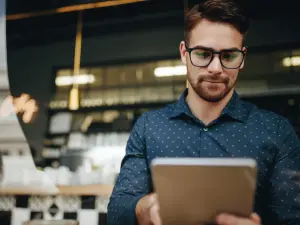 Mann mit Brille und Tablet im Cafe