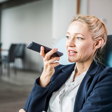 Eine weibliche Führungskraft nimmt eine Nachricht mit dem Handy auf