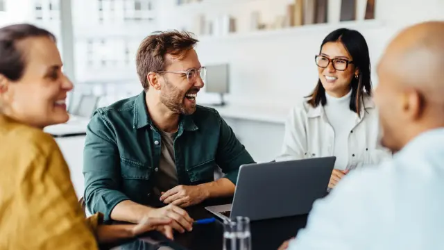Eine Gruppe Kollegen sitzt zusammen und lacht