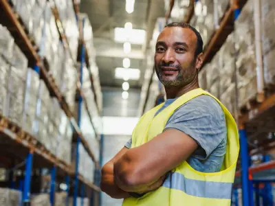 Ein Mann mit Warnwest in einem Lager schaut in die Kamera