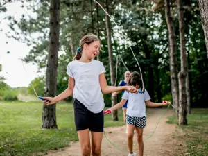 Mädchen mit Springseil auf einem Waldweg