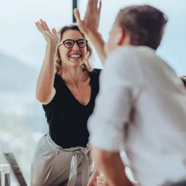 Kolleg*innen feiern Erfolg mit Highfive 