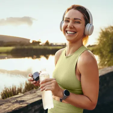 Junge Frau die Kopfhörer auf hat, lächelt nach dem Sport zufrieden. 