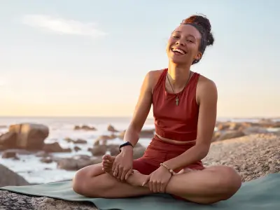 Eine Frau sitzt im Schneidersitz am Strand. 