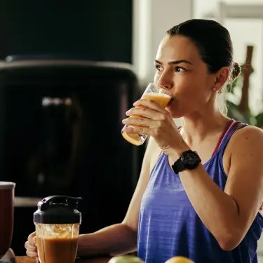 Eine junge sportliche Frau trinkt einen Obst-Smoothie