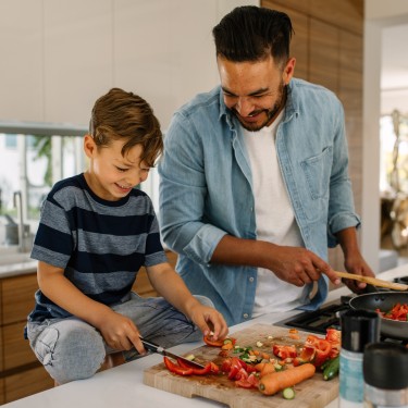 Vater und Sohn bereiten eine Gemüsepfanne vor.