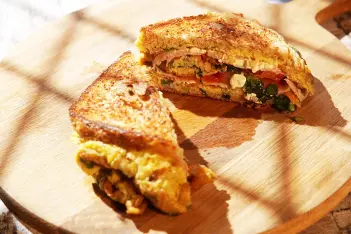 Ein kalorienarmes One Pan Eiersandwich auf einem Holzteller.