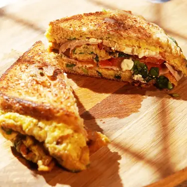 Ein kalorienarmes One Pan Eiersandwich auf einem Holzteller.