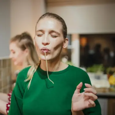 Eine junge Frau mit einer Spaghetti im Mund