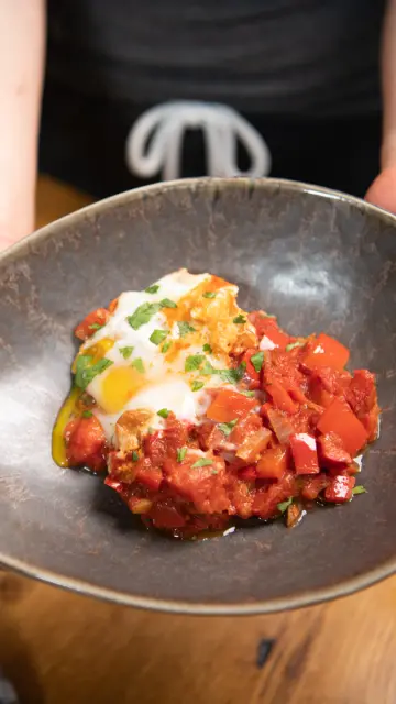 Händer zeigen das Gericht Shakshuka