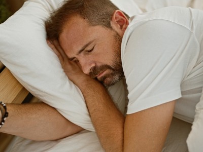 Ein Mann mittleren Alters liegt im Bett und schläft.