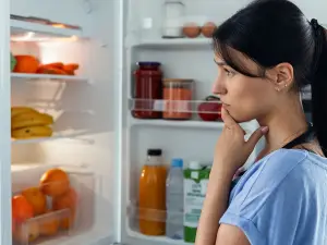 Junge Frau hat die Wahl zwischen Obst und Gebäck. Sie entscheidet sich für das Gebäck.