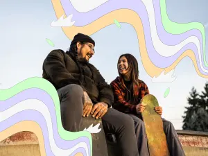 Zwei junge Menschen sitzen auf einer Skaterampe und lachen