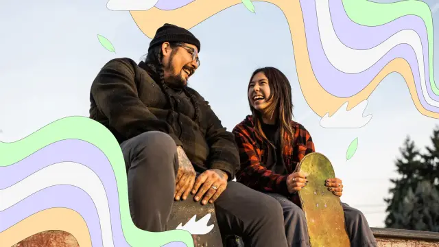 Zwei junge Menschen sitzen auf einer Skaterampe und lachen