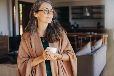 Frau mit einer Tasse in der Hand in ihrem Zuhause