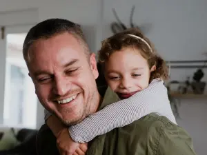 Vater trägt Kind auf dem Arm und beide lächeln