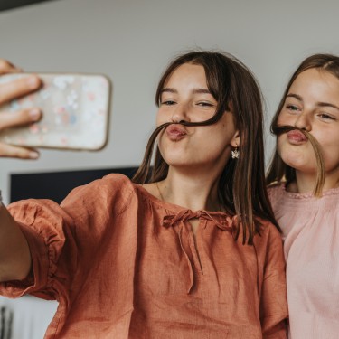 2 junge Mädchen schauen gemeinsam in ein Smartphone.