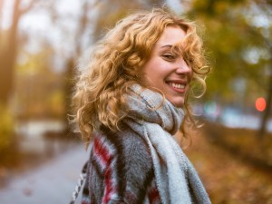 Junge Frau mit Schal läuft durch Herbstlandschaft
