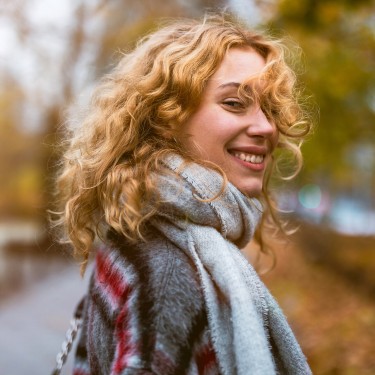Junge Frau mit Schal läuft durch eine Herbstlandschaft