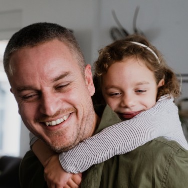 Ein Vater trägt seine Tochter auf der Schulter